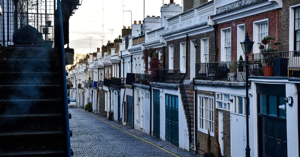 Cobbled street lined with classic townhouses in a quiet London residential district.