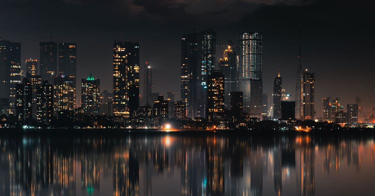 Captivating night view of Mumbai skyline with skyscrapers and reflections on still water.