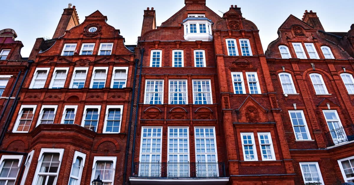 Low-angle view of traditional Victorian townhouse facades in London.